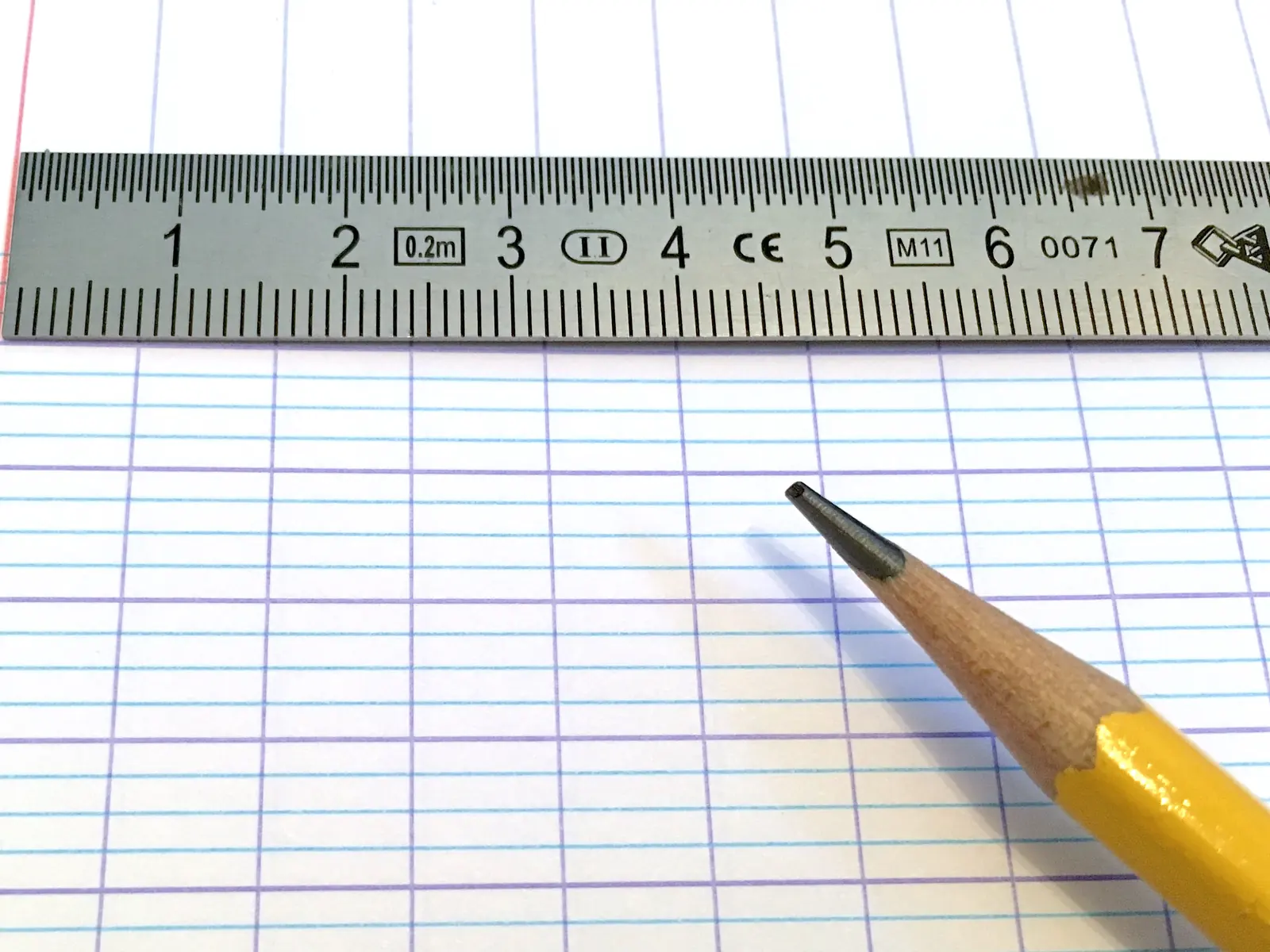 Feuille de cahier à grands carreaux Seyès, avec une règle graduée et un crayon à papier