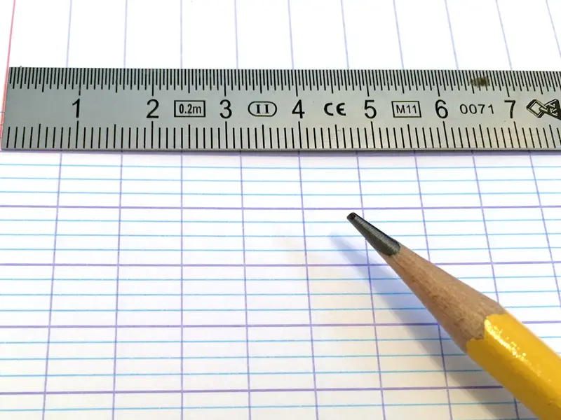 Feuille de cahier à grands carreaux Seyès, avec une règle graduée et un crayon à papier