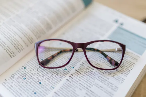 Lunettes de lecture posées sur un dictionnaire ouvert