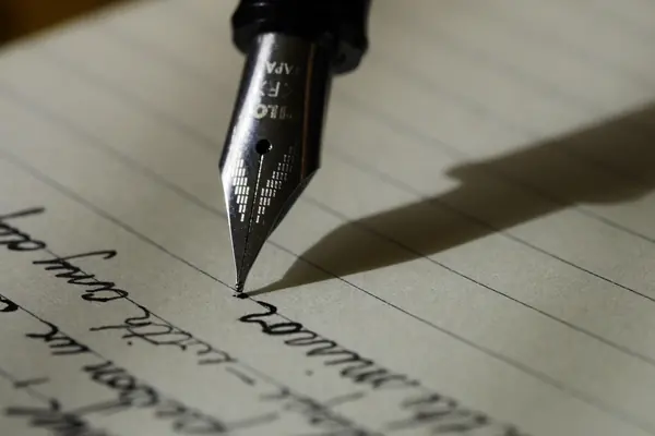 Plume qui écrit à l'encre sur une feuille lignée