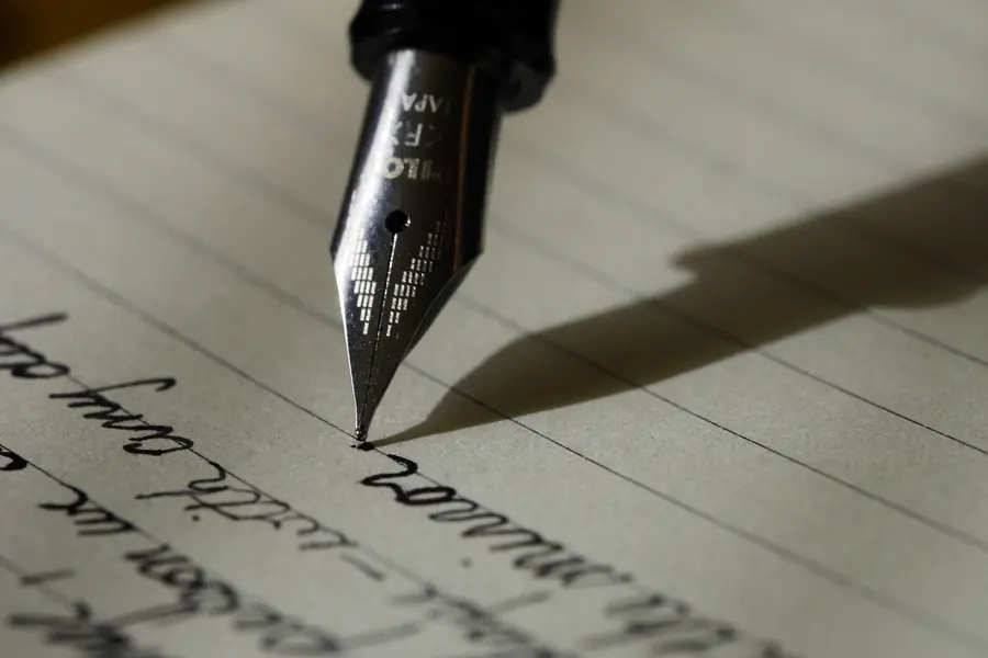 Plume qui écrit à l'encre sur une feuille lignée