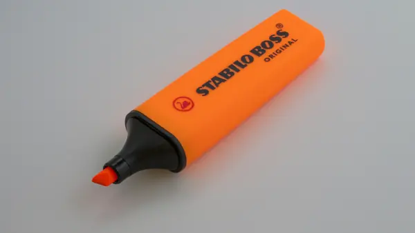 Surligneur orange posé sur une table claire