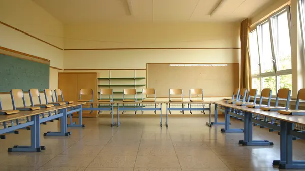 Salle de classe d'école primaire vide, tables alignées et tableau au fond
